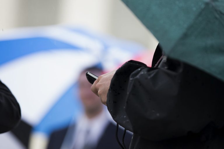 A man checks his cellphone as he waits in line outside the Supreme Court in Washington, Tuesday, April 29, 2014, to hear arguments. (AP Photo)