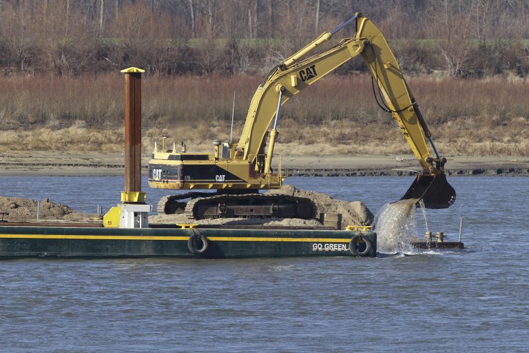   Barges with excavating machinery remove rocks on the Mississippi River Tuesday, Dec. 18, 2012, in Thebes Ill. The Army Corps of Engineers is delaying the use of explosives to blast away treacherous rock pinnacles on the Mississippi River because crews are having so much success removing the rocks with excavating machinery. (AP Photo/Seth Perlman)  