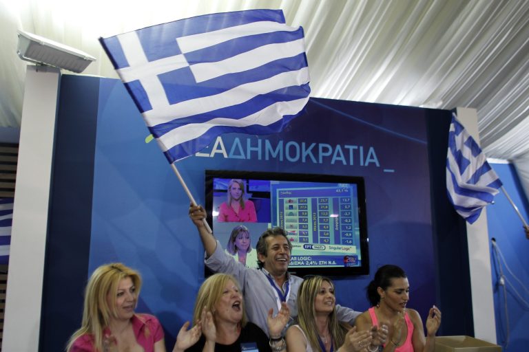   Supporters of the New Democracy conservative party celebrate at an election kiosk at Syntagma square in Athens, Sunday, June 17, 2012. The pro-bailout New Democracy party came in first Sunday in Greece's national election, and its leader has proposed forming a pro-euro coalition government.(AP Photo/Kostas Tsironis)  