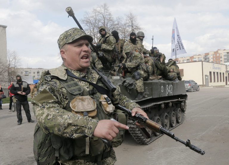 A pro-Russian gunman clears the way for a combat vehicle with gunmen on top in Slovyansk Wednesday, April 16, 2014. The troops on those vehicles wore green camouflage uniforms, had automatic weapons and grenade launchers and at least one had the St. George ribbon attached to his uniform, which has become a symbol of the pro-Russian insurgency in eastern Ukraine. (AP Photo/Efrem Lukatsky)