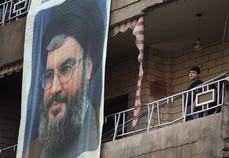 A Lebanese boy stands on his balcony next of a large portrait of Hezbollah leader Sheik Hassan Nasrallah at the site of a car bombing in a southern suburb of Beirut, Lebanon, Wednesday, Jan. 22, 2014. An explosion ripped through a Shiite neighborhood in south Beirut on Tuesday targeting supporters of Lebanon's militant Shiite Hezbollah group. Hezbollah has sent its gunmen to fight alongside Assad's forces, providing a significant boost to the Syrian government's overstretched military. Hezbollah's critics say the group's armed intervention in Syria has stoked sectarian tensions at home and needlessly dragged Lebanon into the maelstrom next door.  (AP Photo/Hussein Malla)