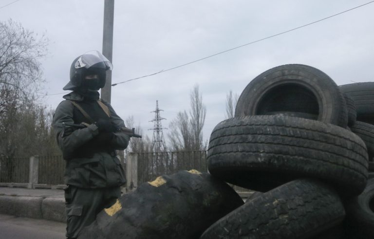 Armed pro-Russian activist stands at a makeshift checkpoint at the entrance into the eastern Ukrainian town of Slovyansk on Saturday, April 12, 2014. Pro-Moscow protesters have seized a number of government buildings in the east over the past week, undermining the authority of the interim government in the capital, Kiev. (AP Photo/Efrem Lukatsky)