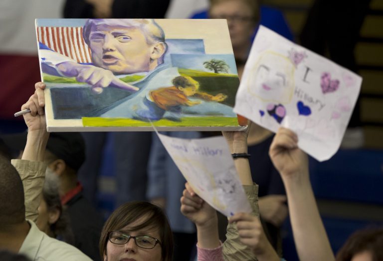 A person on the audience holds up an image of Republican presidential candidate Donald Trump as Democratic presidential candidate Hillary Clinton greets supporters and takes photos during a campaign event at the Grady Cole Center in Charlotte, N.C., Monday, March 14, 2016. (AP Photo/Carolyn Kaster)