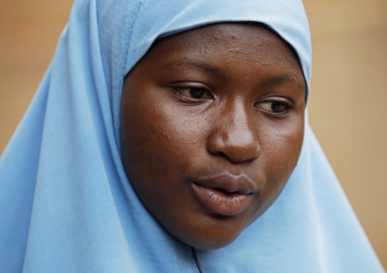 In this Sunday, June 1, 2014 photo, Maimuna Abdullahi sits outside her school in Kaduna, Nigeria. Maimuna wore the scars of an abused woman anywhere: A swollen face, a starved body, and, barely a year after her wedding, a divorce. But for Maimuna, it all happened by the time she was 13. Maimuna is one of thousands of divorced girls in Nigeria who were married as children and then got thrown out by their husbands or simply fled. (AP Photo/Sunday Alamba)