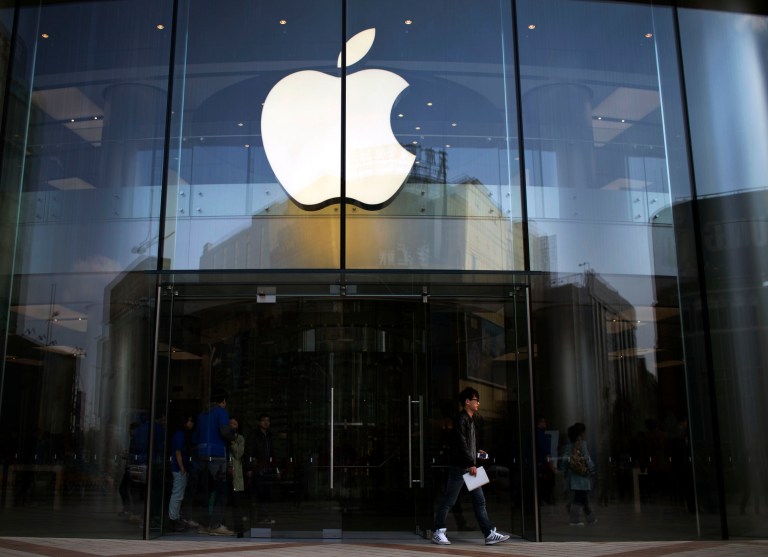 FILE - In this April 1, 2013 photo, a man leaves an Apple store with an iPhone and an iPad in his hands in central Beijing, China. Apple is orchestrating a $3.2 billion acquisition of Beats Electronics, the headphone maker and music streaming distributor founded by hip-hop star Dr. Dre and record producer Jimmy Iovine, according to a Financial Times report published late Thursday, May 8, 2014. (AP Photo/Alexander F. Yuan)