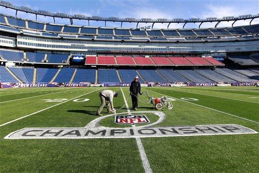 New England Patriots ground crew workers apply paint to an NFL football championship playoff logo at Gillette Stadium in Foxborough, Mass., on Thursday.