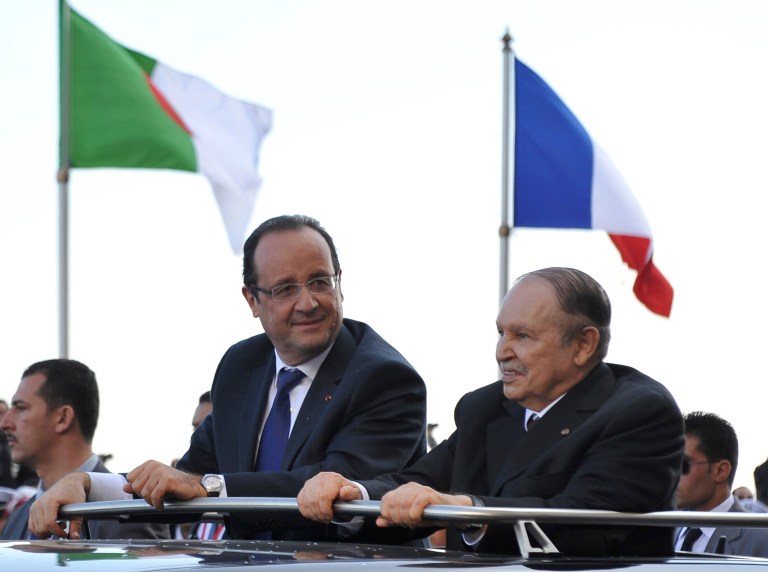   French President Francois Hollande, left, and Algerian President Abdelaziz Bouteflika stand in a car as they drive through Algiers Wednesday, Dec.19, 2012. Hollande arrived Wednesday on a state visit to Algeria, hoping for a clean start in relations after a half-century of tensions with this North Africa nation, once the French empire's most prized colony. (AP Photo/Anis Belghoul)  