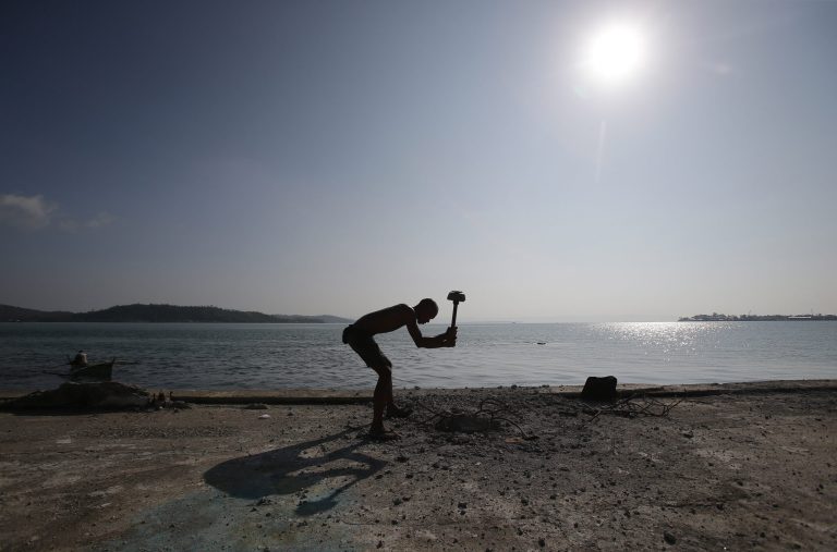 A Filipino typhoon survivor uses a mallet to extract steel bars from a concrete post in Tacloban city, central Philippines on Monday, Oct. 13, 2014. Tacloban was one of the places badly hit by typhoon Haiyan when it struck the country last year. (AP Photo/Aaron Favila)