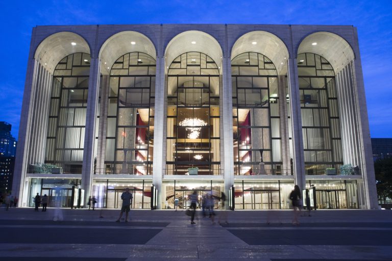 FILE - In this Aug. 1, 2014, file photo, pedestrians walk in front of the Metropolitan Opera house at New York's Lincoln Center. New York's Metropolitan Opera has reached tentative labor deals with two of its largest unions while negotiations continue with 10 more unions in hopes of averting a lockout, the federal Mediation and Conciliation Service announced early Monday, Aug. 18, 2014. (AP Photo/John Minchillo, File)