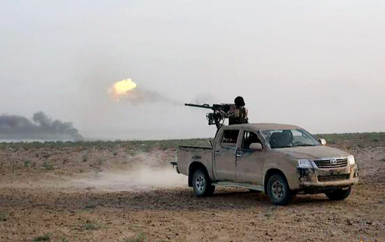 In this picture released on Wednesday, May 20, 2015 by the website of Islamic State militants, an Islamic State fighter fires his weapon during a battle against Syrian government forces on a road between Homs and Palmyra, Syria. (The website of Islamic State militants via AP)