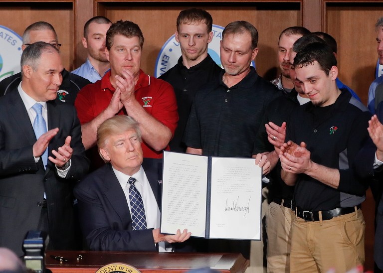 President Donald Trump, accompanied by Environmental Protection Agency Administrator Scott Pruitt, third from left, and Vice President Mike Pence, right, is applauded as he hold up the signed Energy Independence Executive Order on Tuesday at EPA headquarters in Washington. (AP Photo/Pablo Martinez Monsivais)
