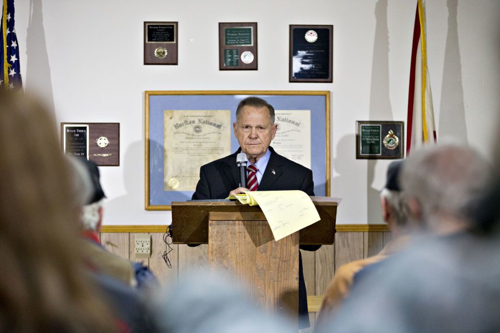 Moore Tries to Play to the Crowd While Avoiding Cameras at Rally