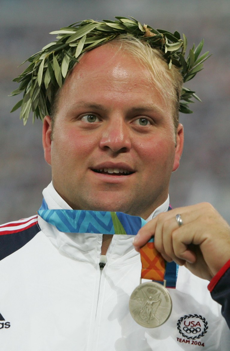   FILE - In this Aug. 20, 2004, file photo, Adam Nelson of the United States, poses on the podium with his silver medalist in the shot put at the summer Olympics in Athens. Shot put gold medalist Yuriy Bilonog of Ukraine, recently was exposed as a drug cheat. The IOC has not said if the medals will be reassigned. But Nelson has a message for those making the call: Do the right thing. (AP Photos/David J. Phillip, File)  