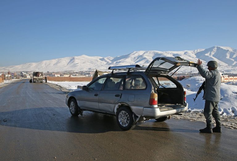 In this Thursday, Jan. 9, 2014 photo, Hekmatullah, an Afghan policeman searches the trunk of a car at a check post in Kabul-Bamiyan road, on the outskirts of Maidan Shahr, capital of Wardak province Afghanistan. Locals call it 