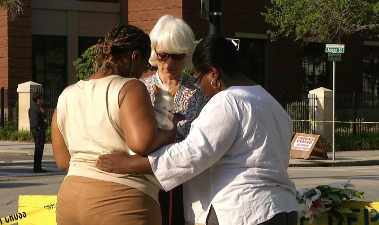 In this image taken from video on Thursday, June 18, 2015, Tarsha Moseley, left, Martha Watson, and Toby Smith pray at a makeshift memorial near Emanuel AME Church in Charleston, S.C. (AP Photo/Alex Sanz)