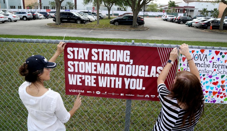 Volunteers hang banners around the perimeter of Marjory Stoneman High School in Parkland, Fla., to welcome back students who will be returning to school Wednesday two weeks after the mass shooting that killed 17 students and staff. (Susan Stocker/South Florida Sun-Sentinel via AP)