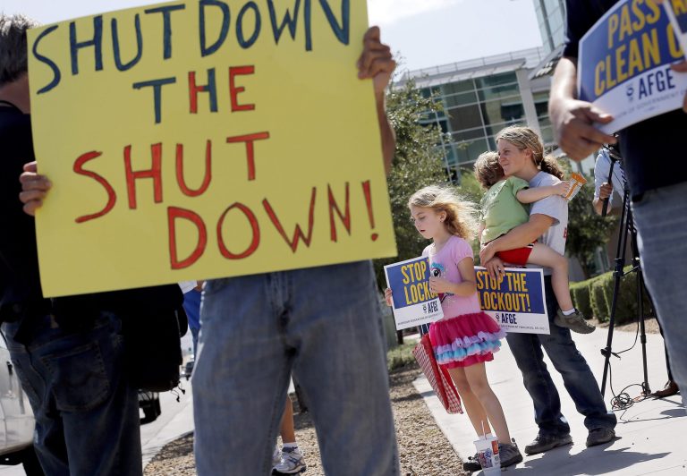 As the federal government shutdown continues, Tory Anderson, right, with her kids Audrey, 7, and Kai, 3, of Goodyear, Ariz., join others as they rally for the Alliance of Retired Americans to end the shutdown in front of the Social Security Administration offices on Wednesday, Oct. 9, 2013, in Phoenix.  Other groups rallying to end the government shutdown include Professional Aviation Safety Specialists, the American Federation of Government Employees AFL-CIO, and Arizona FairShare. (AP Photo/Ross D. Franklin)