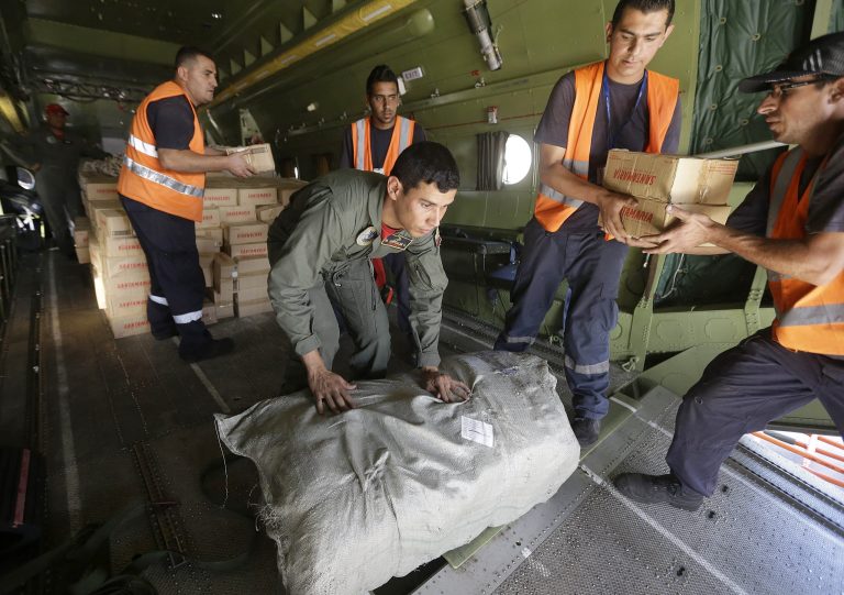   FILE - In this Sept. 16, 2013, file photo, a Venezuelan airman, center, and Lebanese airport workers, right, unload aid supplies from a military plane at Rafik Hariri International Airport in Beirut, Lebanon. As the Syrian crisis rages and debate heats up over Syria's chemical weapons, U.S. officials are fighting a quieter battle: The delivery of nearly $1.3 billion in assistance in a war zone so chaotic that ambulances are used as target practice and aid is halted by armed men at random checkpoints.(AP Photo/Hussein Malla)  