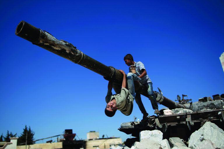 A boy looks back while he and another boy play on a Syrian military tank, destroyed during fighting with the Rebels, in the Syrian town of Azaz, on the outskirts of Aleppo, Sunday, Sept. 2, 2012. (AP Photo/Muhammed Muheisen)