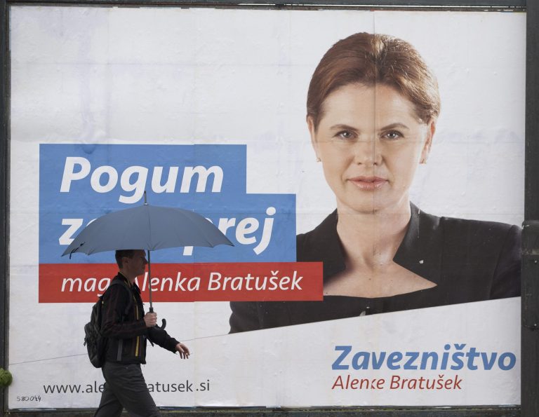 In this photo taken Thursday, July 10, 2014, a pedestrian walks past an election poster of outgoing prime minister Alenka Bratusek, in Ljubljana, Slovenia. Slovenia is holding a snap parliamentary vote on Sunday to choose a third government in three years. The text on poster reads: 