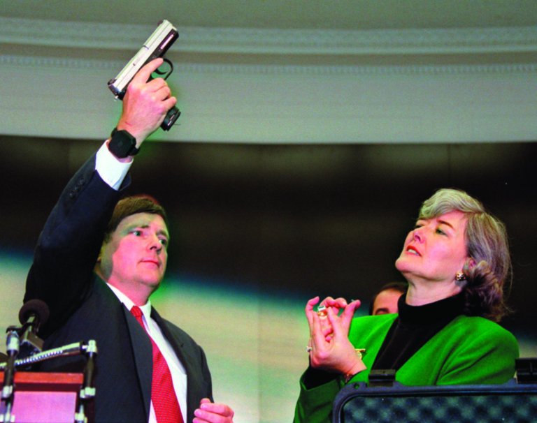 ADVANCE FOR MONDAY JAN. 28 AND THEREAFTER - FILE - In this Wednesday Sept. 18, 1996, file photo, Rep. Pat Schroeder, D-Colo. reacts as Colt Manufacturing Vice President Doug Overbury shows his company's Smart Gun during a Capitol Hill news conference. The gun, a standard-looking .40-caliber, semi-automatic pistol can only be activated from a pea-size radio transmitter worn on the wrist of an authorized shooter. When the White House recently called for pushing ahead with such new technology as part of President Obama's plan to cut gun violence, the administration did not mention the concept's embattled past. As with so much else in the nation's long-running divisions over gun rights and regulation, what sounds like a futuristic vision is, in fact, an idea that has been kicked around for years, sidelined by intense suspicion, doubts about feasibility and pressure tactics. (AP Photo/Mark Wilson)
