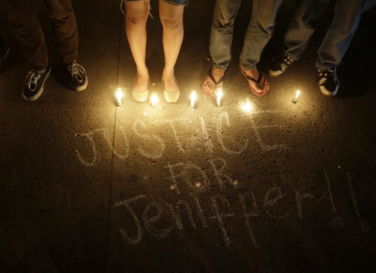Protesters, mostly supporters of LGBT (Lesbians, Gays, Bisexuals and Transgenders), stand next to a scribbled message during a candlelight protest to demand justice in the killing of a Filipino transgender Jeffrey 