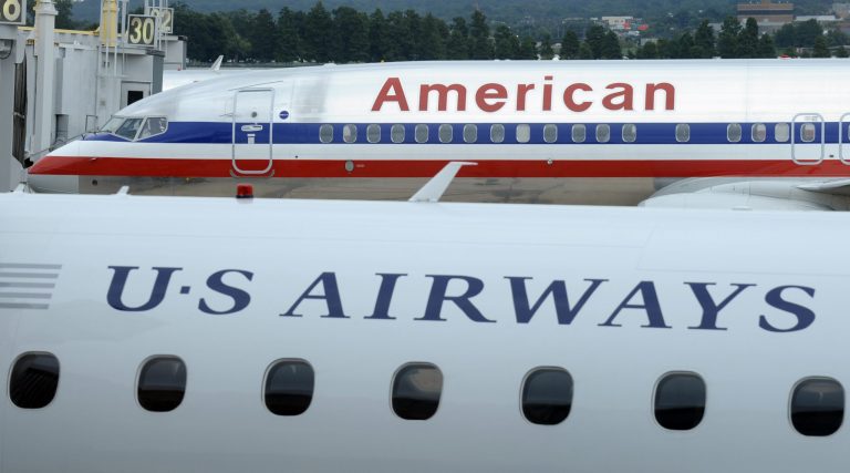 FILE - This Tuesday, Aug. 13, 2013 file photo shows an American Airlines plane and a US Airways plane at parked at Washington's Ronald Reagan National Airport. On Tuesday, Nov. 12, 2013, the Justice Department says it has reached an agreement to allow the merger of the two airlines. The agreement requires them to scale back the size of the merger at key airports in Washington and other big cities. (AP Photo/Susan Walsh)