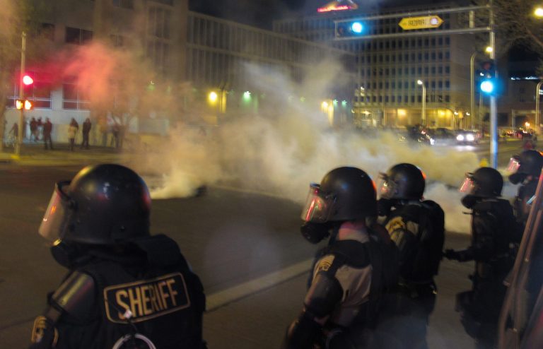 Riot police launch tear gas toward activists in downtown Albuquerque, N.M. following a 10-hour protest around the city, Sunday, March 30, 2014. Hundreds of protesters marched past riot police in Albuquerque on Sunday, days after a YouTube video emerged threatening retaliation for a recent deadly police shooting. The video, which bore the logo of the computer hacking collective Anonymous, warned of a cyberattack on city websites and called for the protest march. (AP Photo/Russell Contreras)