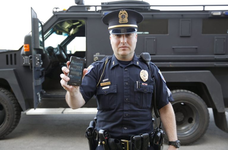 In a May 6, 2014 photo, Sgt. Andres Wells of the Kalamazoo Dept. of Public Safety, who successfully used text messaging to negotiate with a suicidal robbery suspect during a 2011 standoff, stands next to his armored vehicle. With 6 billion text messages exchanged daily in the United States, texting is becoming a more frequent part of police crisis negotiations. (AP Photo/Mark Bugnaski)