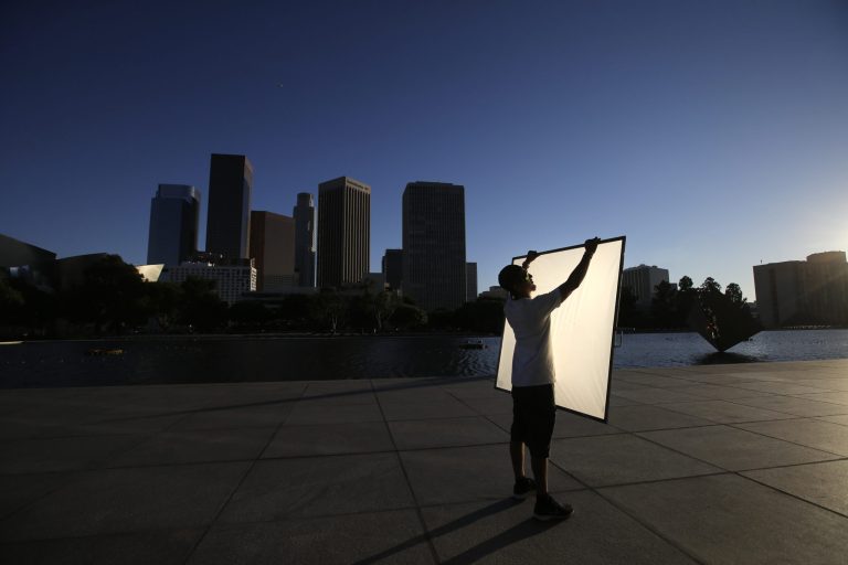 FILE - In this photo taken on Thursday, Aug. 14, 2014, production assistant Adrien Noriega holds a reflector before a film shoot outside the Department of Water and Power headquarters in Los Angeles. Hoping to keep film productions from fleeing California for other states and countries, lawmakers have moved to quadruple tax subsidies for location shooting. (AP Photo/Jae C. Hong, File)