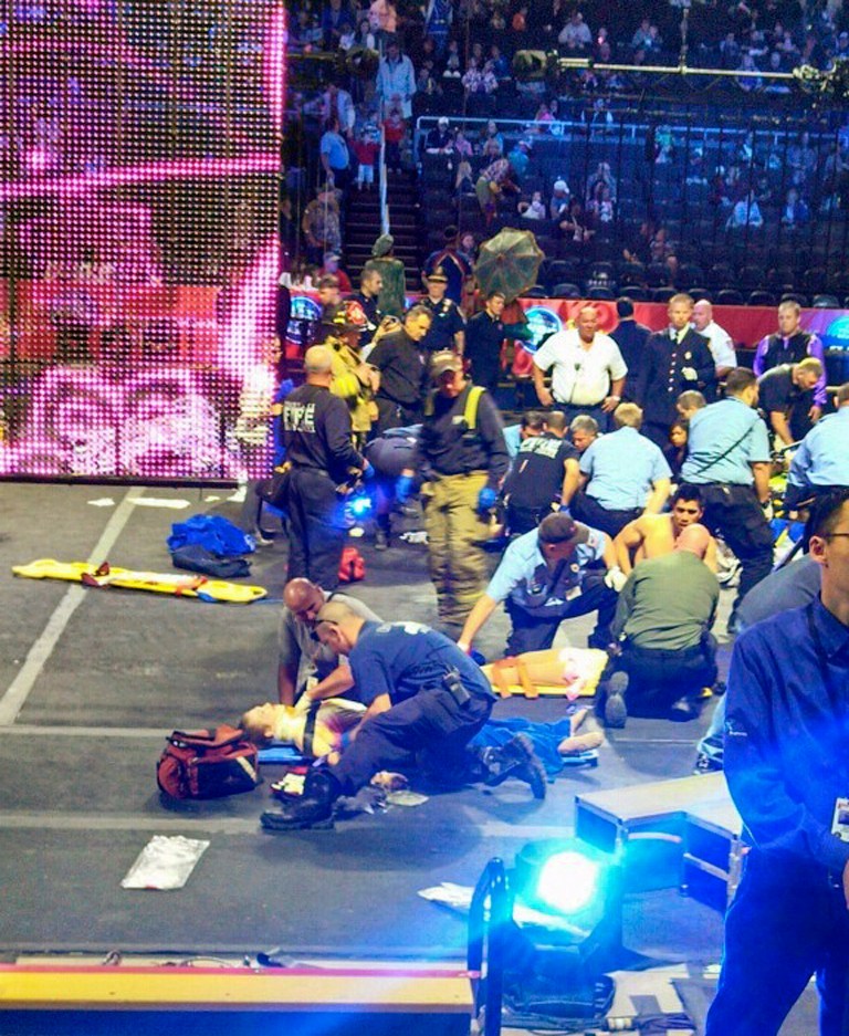 FILE - In this May 4, 2014 file photo provided by Rosa Viveiros, first responders work at the center ring after a platform collapsed during an aerial hair-hanging stunt at the Ringling Brothers and Barnum and Bailey Circus in Providence, R.I. Seven of the eight hair-hanging acrobats who fell to the Dunkin' Donuts Center floor during the stunt have hired a Chicago-based law firm to represent them, the firm announced Monday, June 16, 2014. (AP Photo/Rosa Viveiros, File) MANDATORY CREDIT