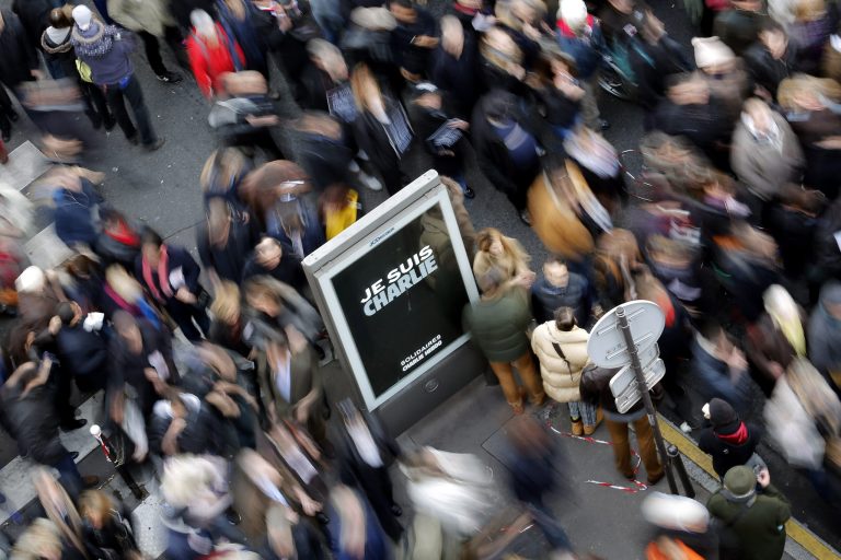 The crowd walk by a sign 