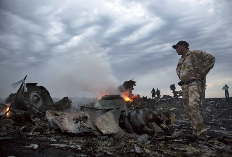 FILE - In this July 17, 2014, file photo, people walk amongst the debris, at the crash site of a passenger plane near the village of Hrabove, Ukraine. More travelers are flying than ever before, creating a daunting challenge for airlines: continue to keep passengers safe in an ever more crowded airspace.  (AP Photo/Dmitry Lovetsky, File)