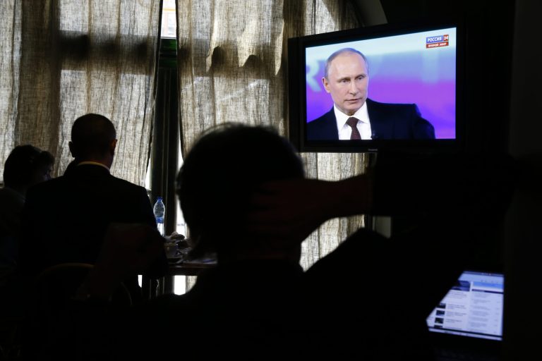 Reporters listen to Russian President Vladimir Putin's speech, displayed on TV screens during a nationally televised question-and-answer session in Moscow, Thursday, April 17, 2014. Russia's President Vladimir Putin on Thursday dismissed claims that Russian special forces are fomenting unrest in eastern Ukraine as 