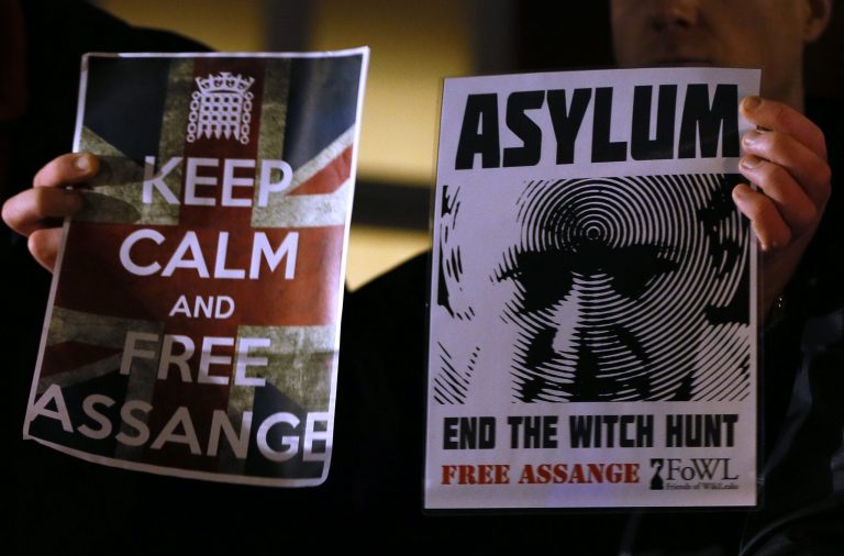   Supporters hold banners as they wait for Julian Assange, founder of WikiLeaks to speak to the media and members of the public from a balcony at the Ecuadorian Embassy in London, Thursday, Dec. 20, 2012. Assange who faces extradition to Sweden over sexual assault, claims which he denies, took refuge in the embassy in June. (AP Photo/Kirsty Wigglesworth)  