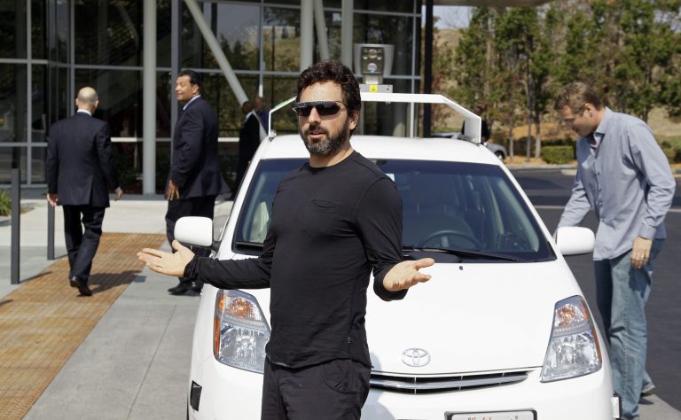 FILE - In this Sept. 25, 2012 file photo, Google co-founder Sergey Brin gestures after riding in a driverless car with California Gov. Edmund G Brown Jr., left, and state Senator Alex Padilla, second from left, to a bill signing for driverless cars at Google headquarters in Mountain View, Calif. The California Department of Motor Vehicles on Tuesday, March 11, 2014, held a public hearing to solicit ideas on how to integrate driverless cars, sometimes called 