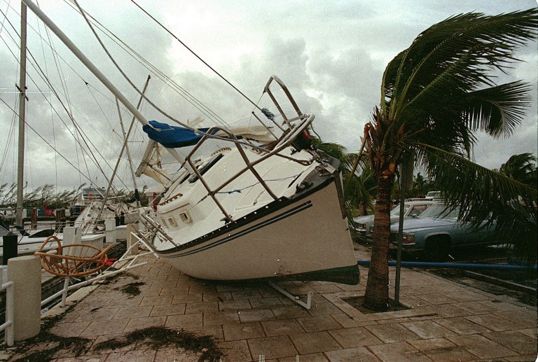 FILE - In this Aug. 24, 1992 file photo, a sailboat sits on a sidewalk at Dinner Key in Miami after it was washed ashore by Hurricane Andrew. Global warming is rapidly turning America into a stormy and dangerous place, with rising seas and disasters upending lives from flood-stricken Florida to the wildfire-ravaged West, the National Climate Assessment concluded Tuesday, May 6, 2014.  (AP Photo/Terry Renna, File)