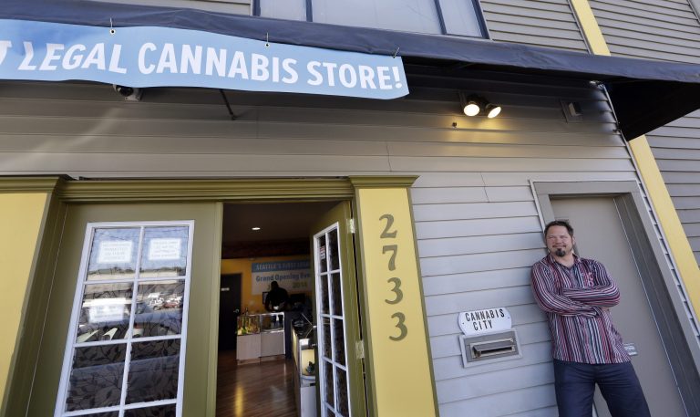 Cannabis City owner James Lathrop briefly leans against the exterior of his new recreational marijuana store Monday, July 7, 2014, in Seattle. The shop will be the first and, initially, only store in Seattle to legally sell recreational pot when sales begin Tuesday. (AP Photo/Elaine Thompson)