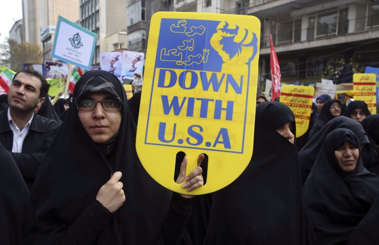 An Iranian demonstrator holds an anti-U.S. placard during an annual rally in front of the former U.S. Embassy in Tehran, marking 36th anniversary of the seizure of the embassy by militant Iranian students, Iran, Wednesday, Oct. 4, 2015. The annual state-organized rally Wednesday drawing greater attention this year, as Iranian hardliners are intensifying a campaign to undermine President Hassan Rouhani's outreach to the West following a landmark nuclear deal reached with world powers in July.(AP Photo/Vahid Salemi)