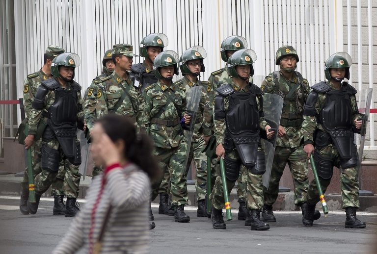 FILE - In this May 23, 2014 file photo, paramilitary policemen with shields and batons patrol near the People's Square in Urumqi, China's northwestern region of Xinjiang.  So far this month, police in China's restive western region of Xinjiang have broken up 23 terror and religious extremism groups and caught over 200 suspects, state media reported Monday, May 26. (AP Photo/Andy Wong, File)