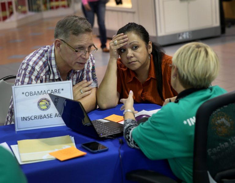 Angel Rivera (L) and his wife Wilma Rivera sit with, Amada cantera, an insurance agent with Sunshine Life and Health Advisors as they try to purchase health insurance under the Affordable Care Act at the kiosk setup at the Mall of Americas on December 22, 2013 in Miami, Florida. (Photo by Joe Raedle/Getty Images)