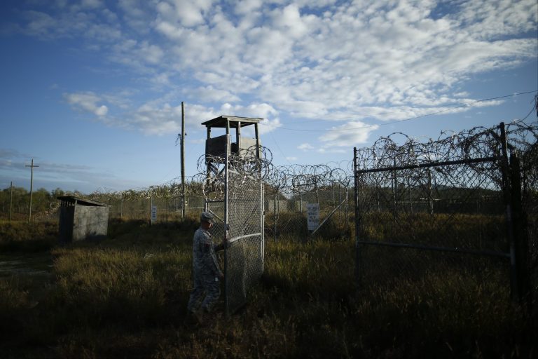 In this photo reviewed by the U.S. military, a soldier closes the gate at the now abandoned Camp X-Ray, which was used as the first detention facility for al-Qaida and Taliban militants who were captured after the Sept. 11 attacks at Guantanamo Bay Naval Base, Cuba, Thursday, Nov. 21, 2013.  Detainees were housed in open air pens until the completion of Camp Delta in April 2002. Many detainees at Guantanamo Bay may be closer to heading home under a bipartisan deal reached in Congress that gives President Barack Obama a rare victory in his fight to close the prison for terror suspects. (AP Photo/Charles Dharapak)