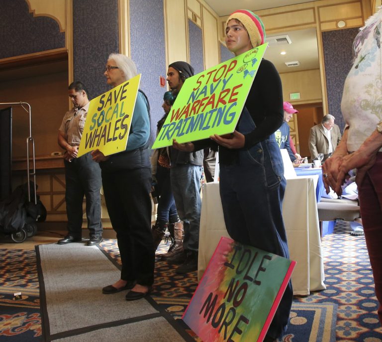 Demonstrators hold signs stating their position against US Navy training exercises off the California Coast, during a California Costal Commission meeting Friday, March 8, 2013 in San Diego. The U.S. Navy opposes state restrictions on an explosives and sonar training program off the Southern California coast that critics fear will threaten whales and other sea mammals, state regulators were told Friday. (AP Photo/Lenny Ignelzi)