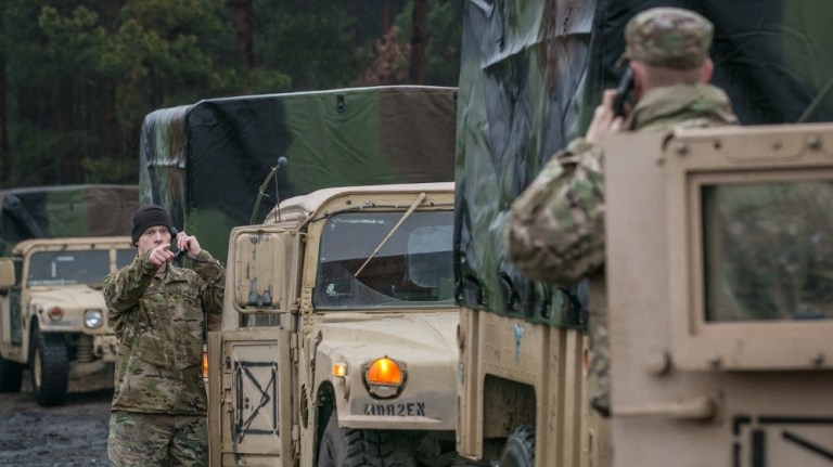 Spc. Caleb L. Gardner, left, an all source intelligence analyst conducts radio checks with other vehicles within a convoy at Zagan, Poland, part of Allied Spirit VIII exercises in 2018.
