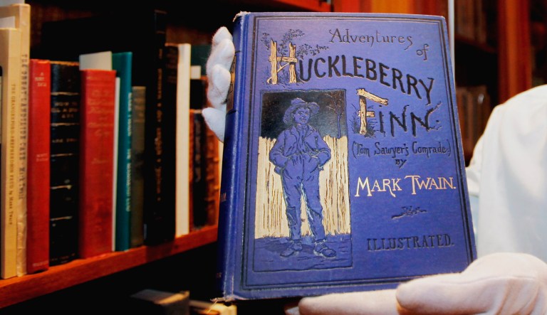 In this photo taken Feb. 23, 2010, Mark Woodhouse, Mark Twain archivist, holds a first edition "Adventures of Huckleberry Finn" book by Mark Twain at the Mark Twain Archive at Elmira College in Elmira, N.Y.