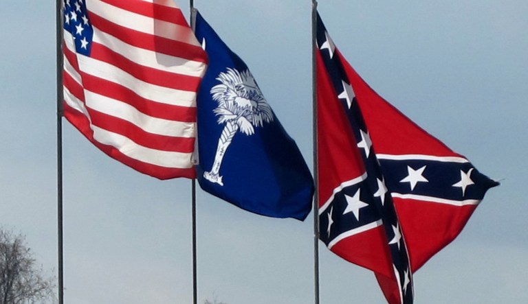 In this photo taken March 25, 2011 on Johns Island, S.C., the United States, South Carolina and Confederate flags fly beside a tent near a field where the Battle of Charleston is re-enacted each year. For Civil War re-enactors, the sesquicentennial of the War Between the States means a four-year stretch of once-in-a-lifetime chances to practice the sometimes derided passion at its peak, and something more.