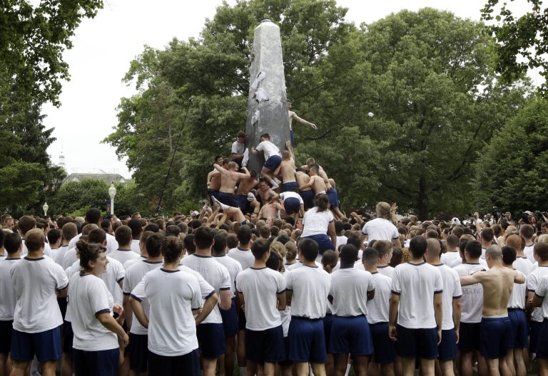 Plebes climb the lard-covered Herndon Monument on the United States Naval Academy campus in Annapolis, Md., Tuesday, May 22, 2012. As the rite of passage after the Midshipmen's first year on campus, plebes must remove a "dixie cup" hat from the monument's 21-foot peak and replace it with an upperclassman's hat.