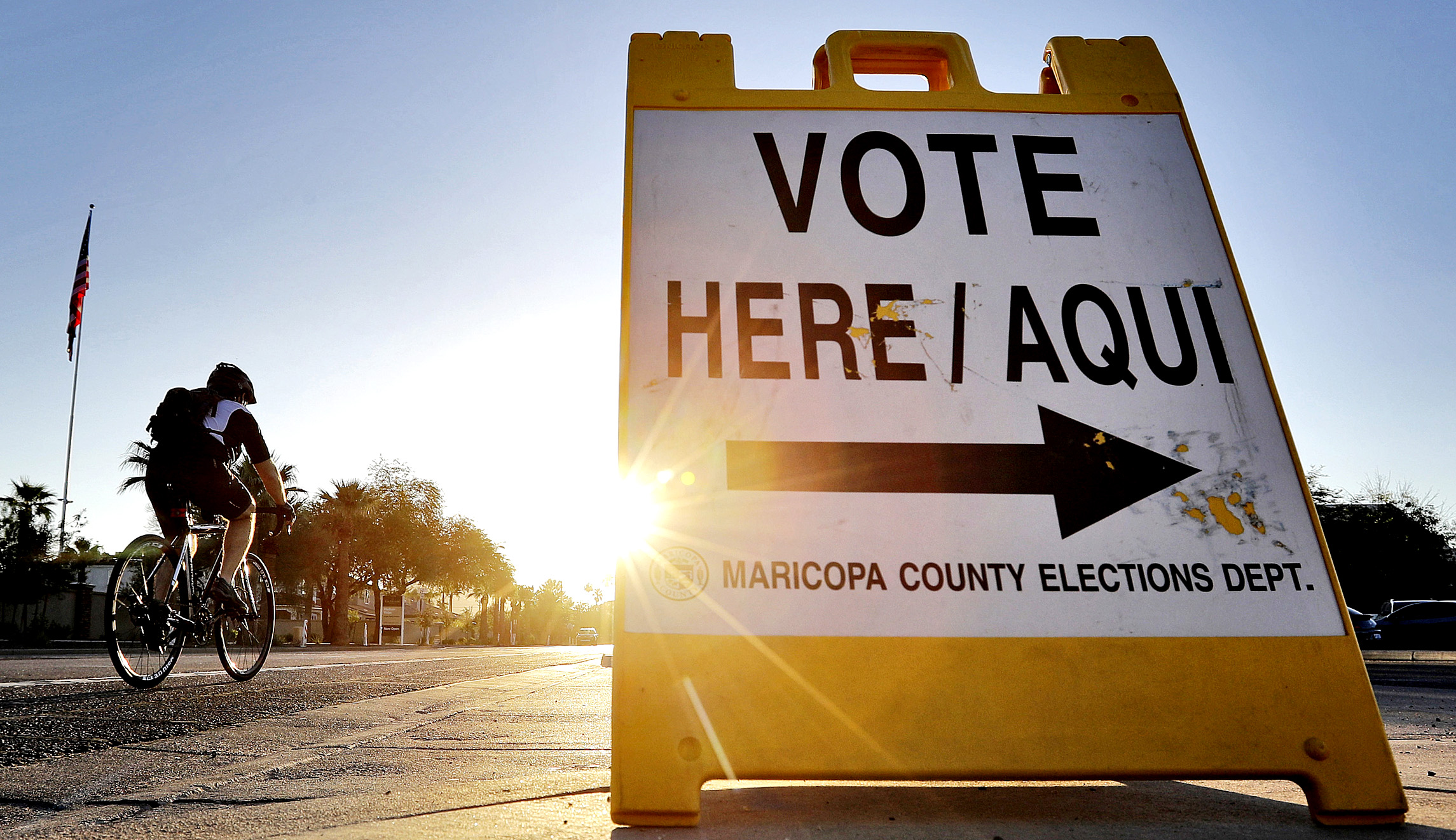 A cyclist rides past a sign directing voters to an election voting station in Phoenix.