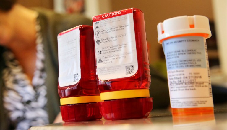 Prescription bottles with pills are seen on a table.