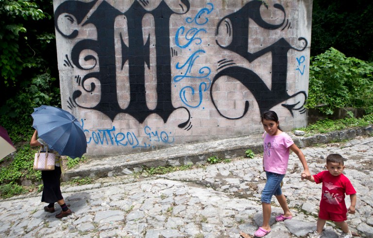Children in El Salvador walk by graffiti celebrating the gang MS-13. (AP Photo/Esteban Felix, File)